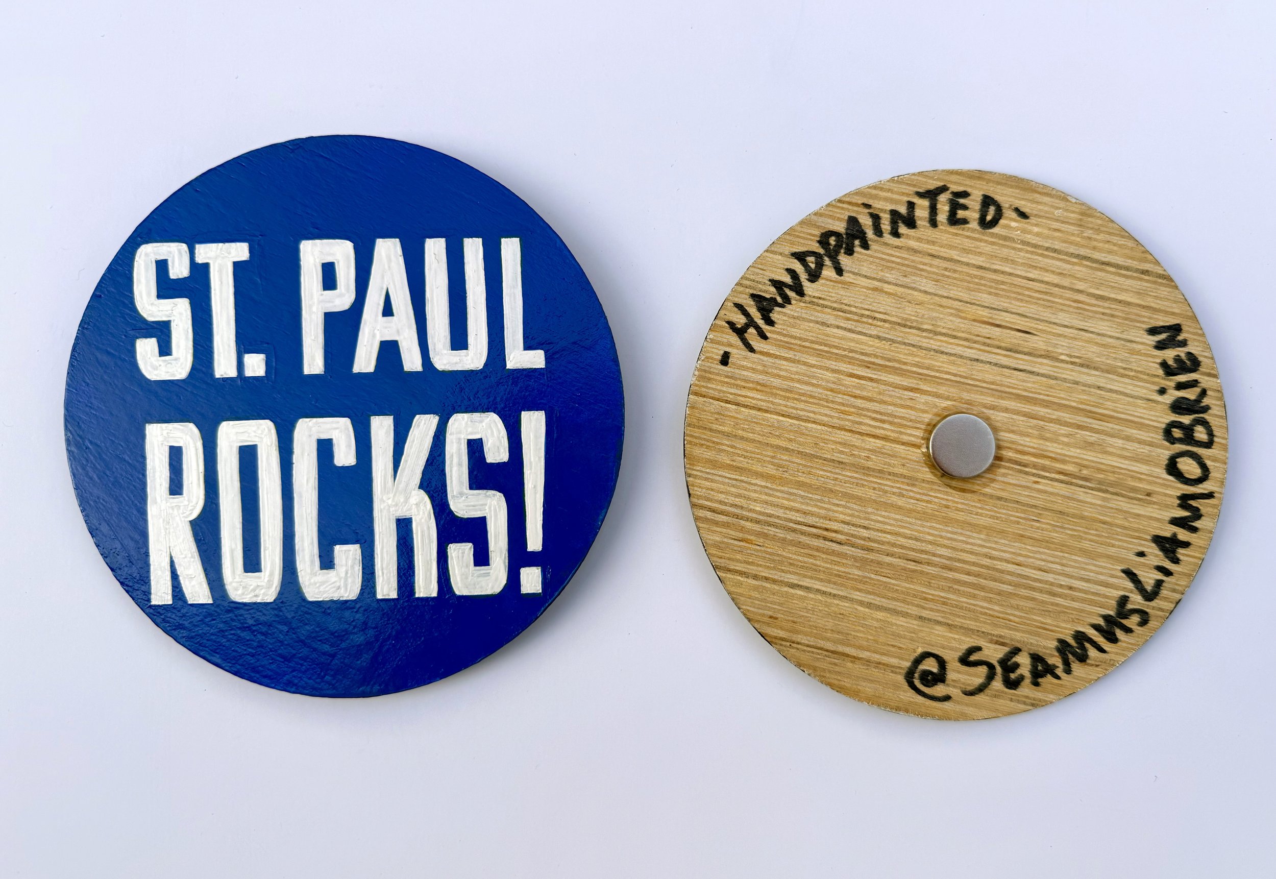 Blue circle with white text that says, 'St. Paul Rocks!' and the reverse side with hand written text in sharpie