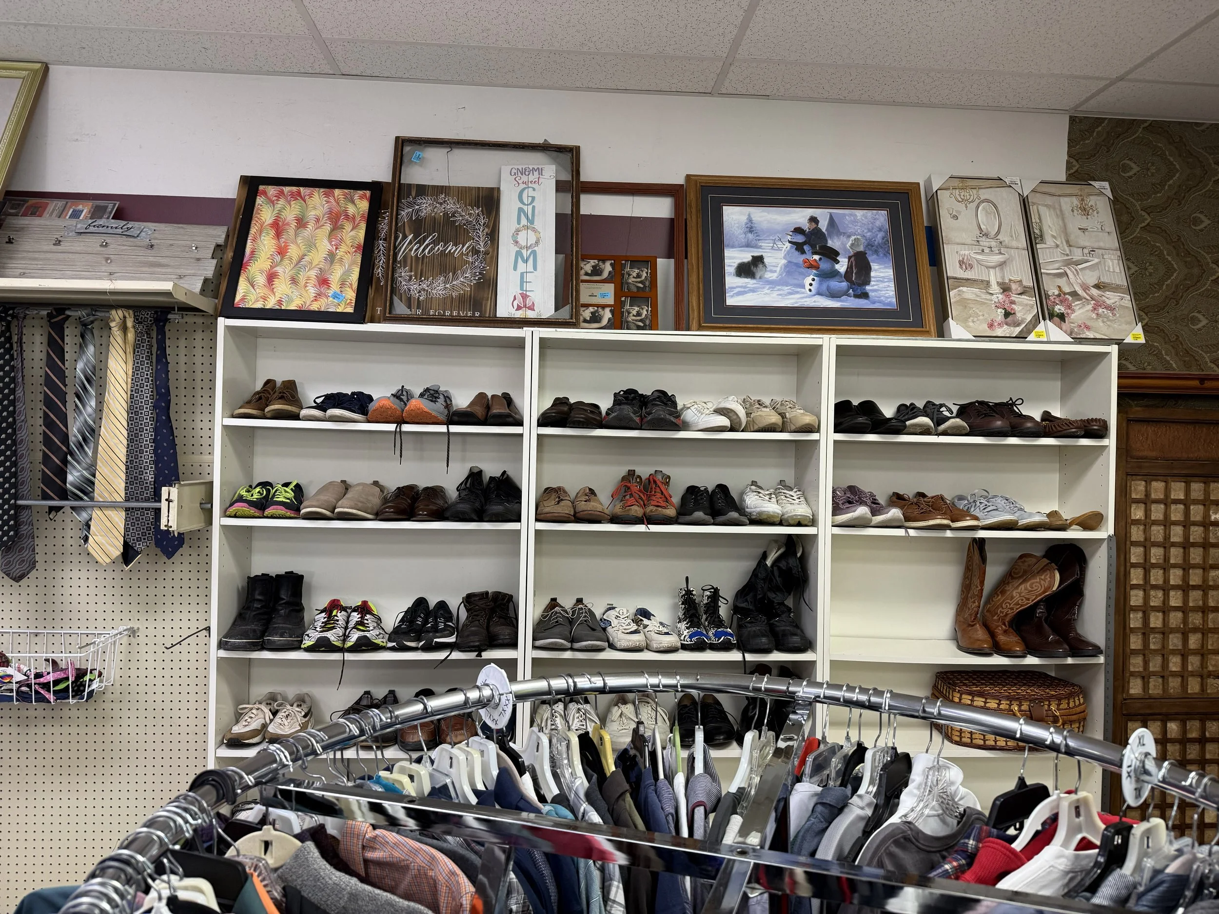 Paintings, shoes, and shirts on display in a store.