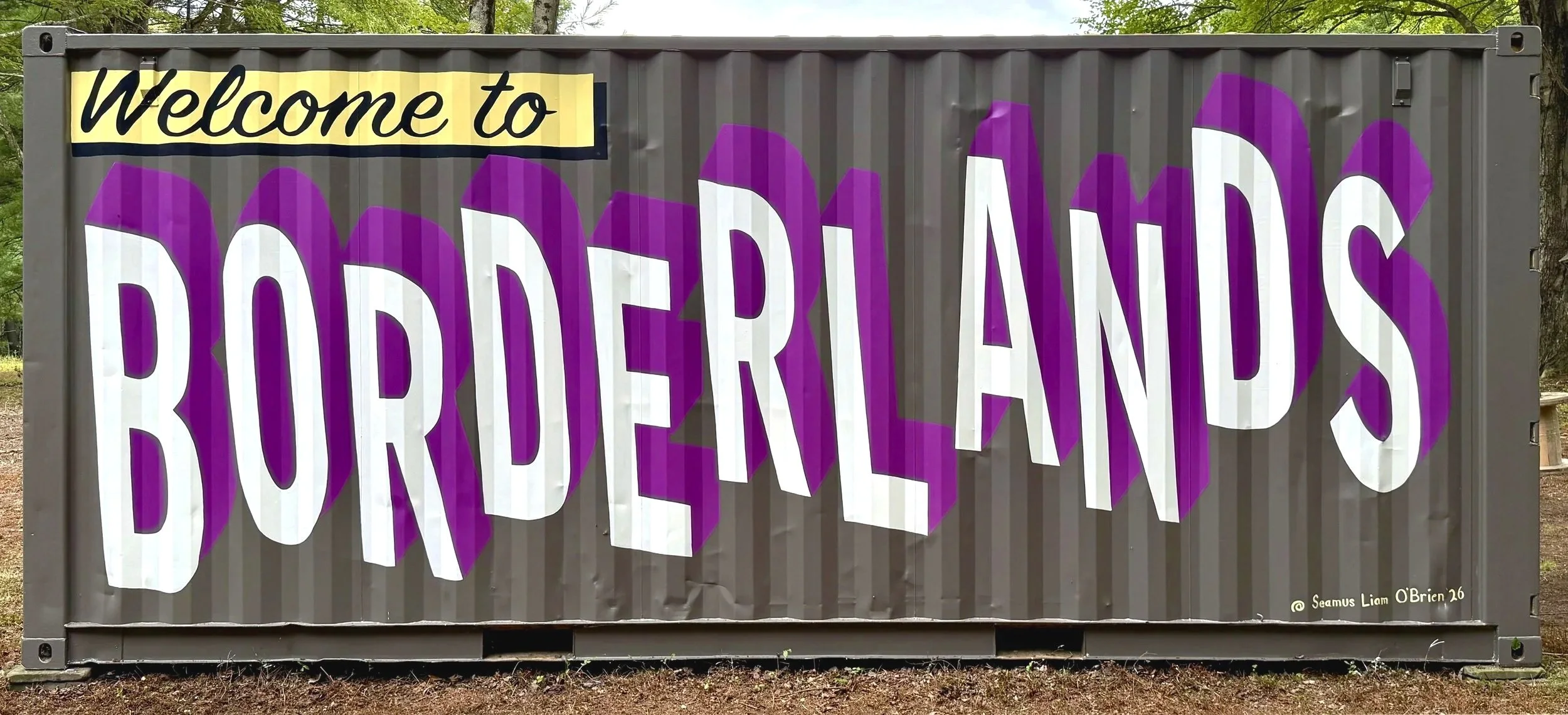 'Welcome to Borderlands' painted with white and purple letters on the side of a grey shipping container