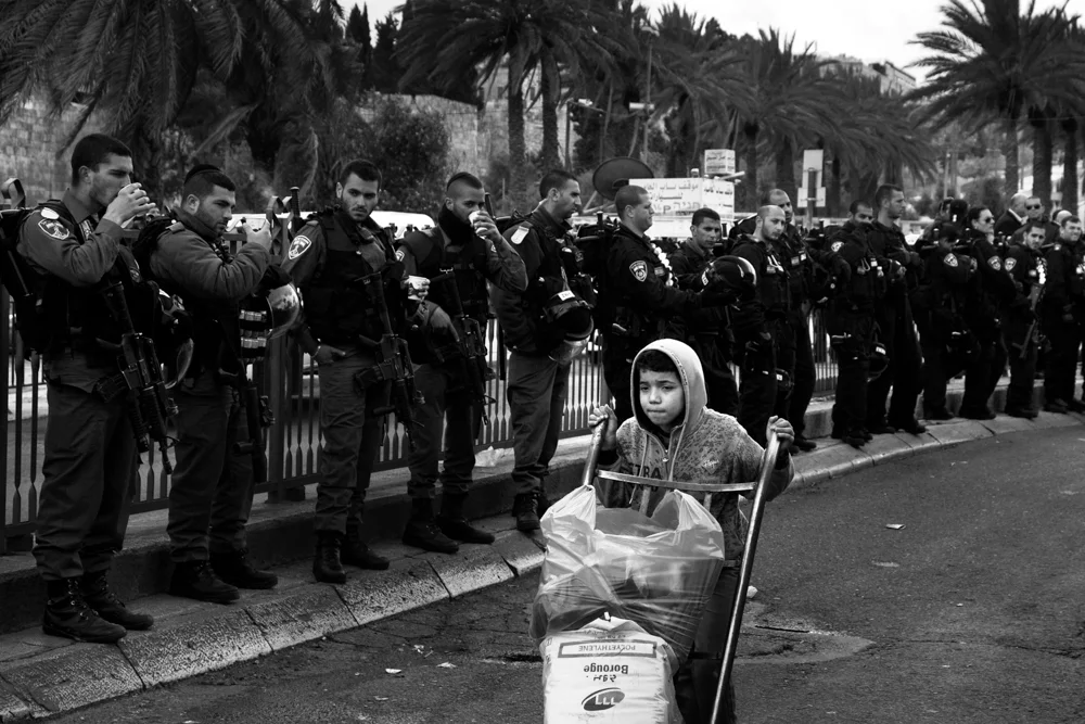  A young Palestinian carrying goods under the eyes of Israeli Police, during a Palestinian demonstration at Damascus Gate in Jerusalem. 