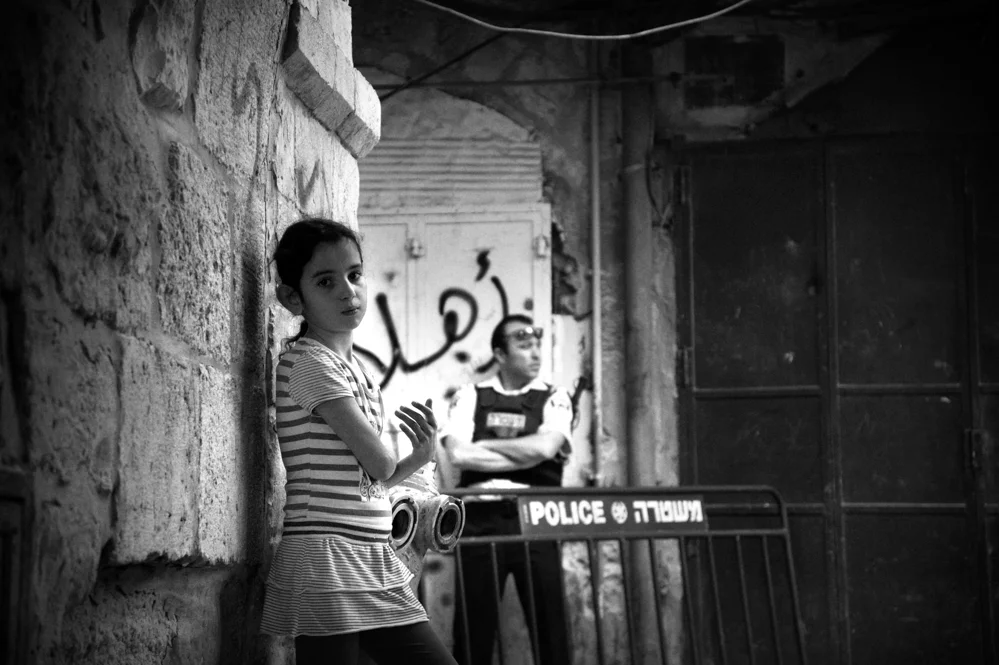  A Palestinian girl standing by a Israeli checkpoint, during entry restriction at the Al-Aqsa Mosque Compound. Old City of Jerusalem. 