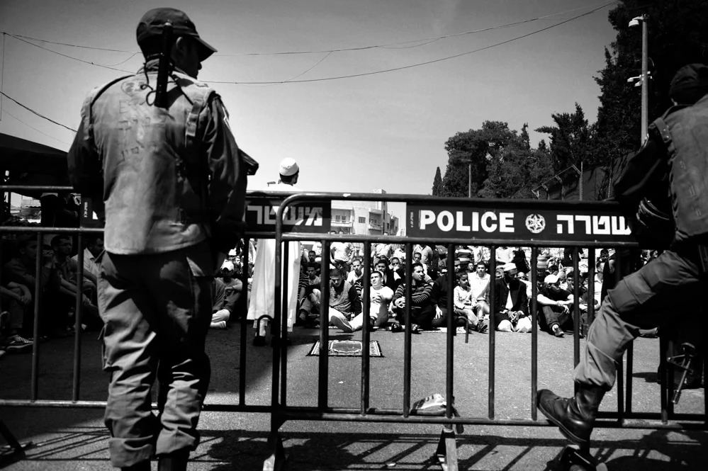  Palestinian perform Friday prayers in front at a check point in Damascus Gate, during the entry restrictions for Palestinians into the old city of Jerusalem. 
