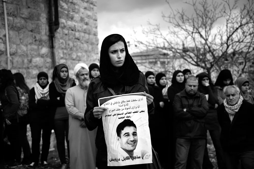  A friend of Saji Sayel Darwish hold a photo during his funeral. Saji was shoot the night before after supposedly attacking Israeli soldiers on the road to Ramallah. Beitin; Palestinian Territories, 11/03/2014 