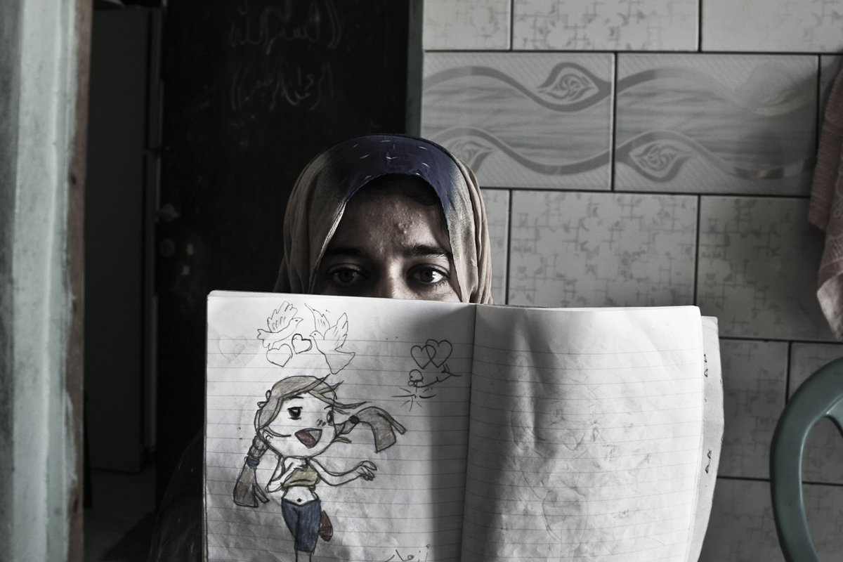 Sahar displays her notebook where she draws and writes her thoughts. She suffers from a deformation of her upper throat that affects her hearing and speech. Due to her condition she spends a lot of time at home. Two months ago she decided to join th