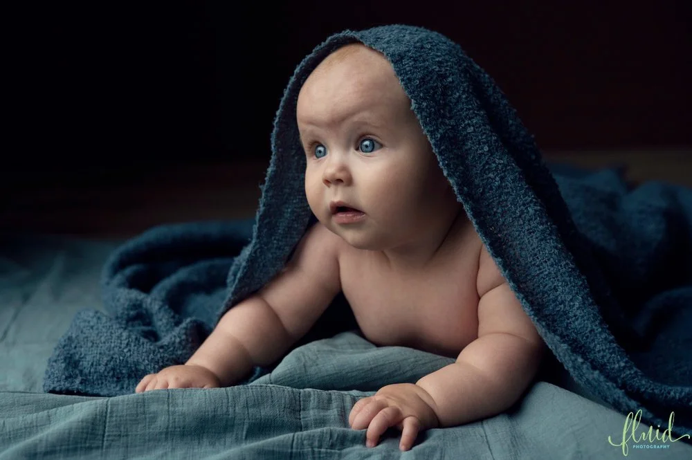 Baby peaking under a blanket.