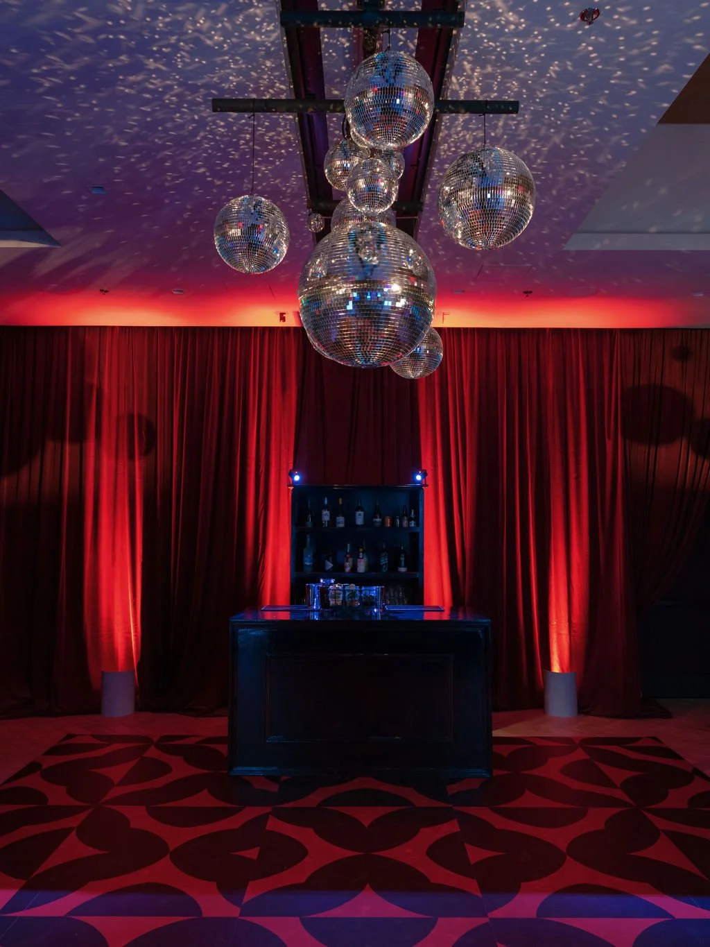 Wedding after-party bar with disco balls and red drapery