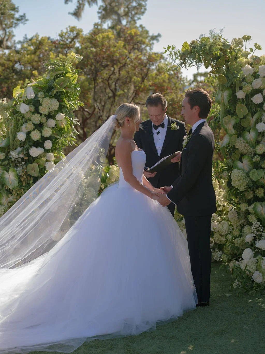 Bride and groom holding hands during their outdoor wedding ceremony