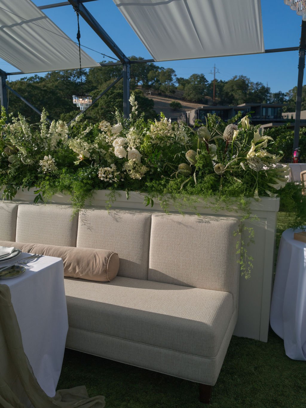 Wedding reception banquette with white floral hedge