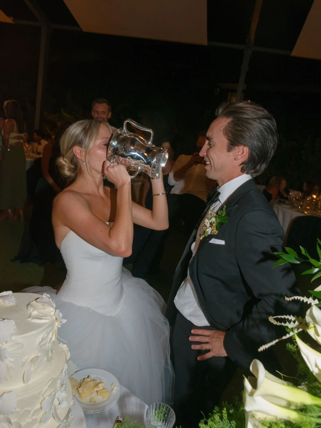 Bride drinking from an antique silver loving cup at her wedding reception