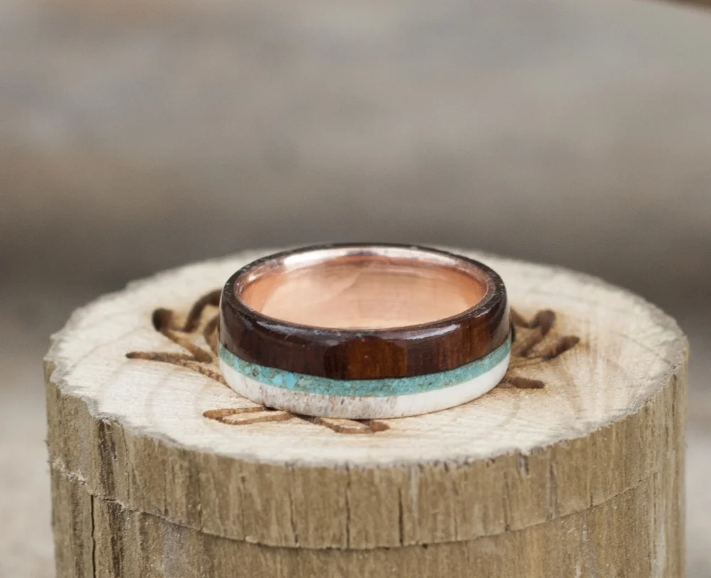 Top view. Wood, gold and antler wedding ring with turquoise inlays, line with rose gold. Rose gold men's wedding ring band.