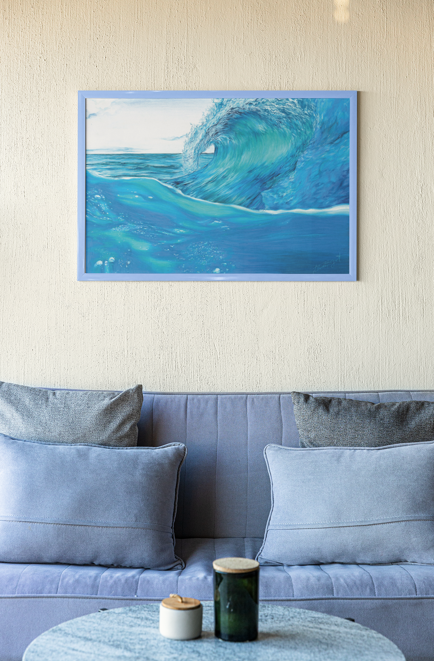 ocean wave art print in frame hanging over blue couch