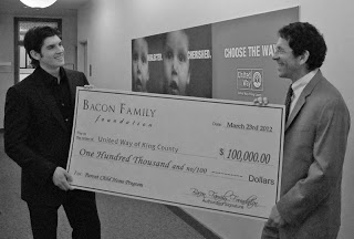 Tony Bacon presents a check to United Way CEO Jon Fine to help launch the Parent Child Home Visit Program on the Eastside.