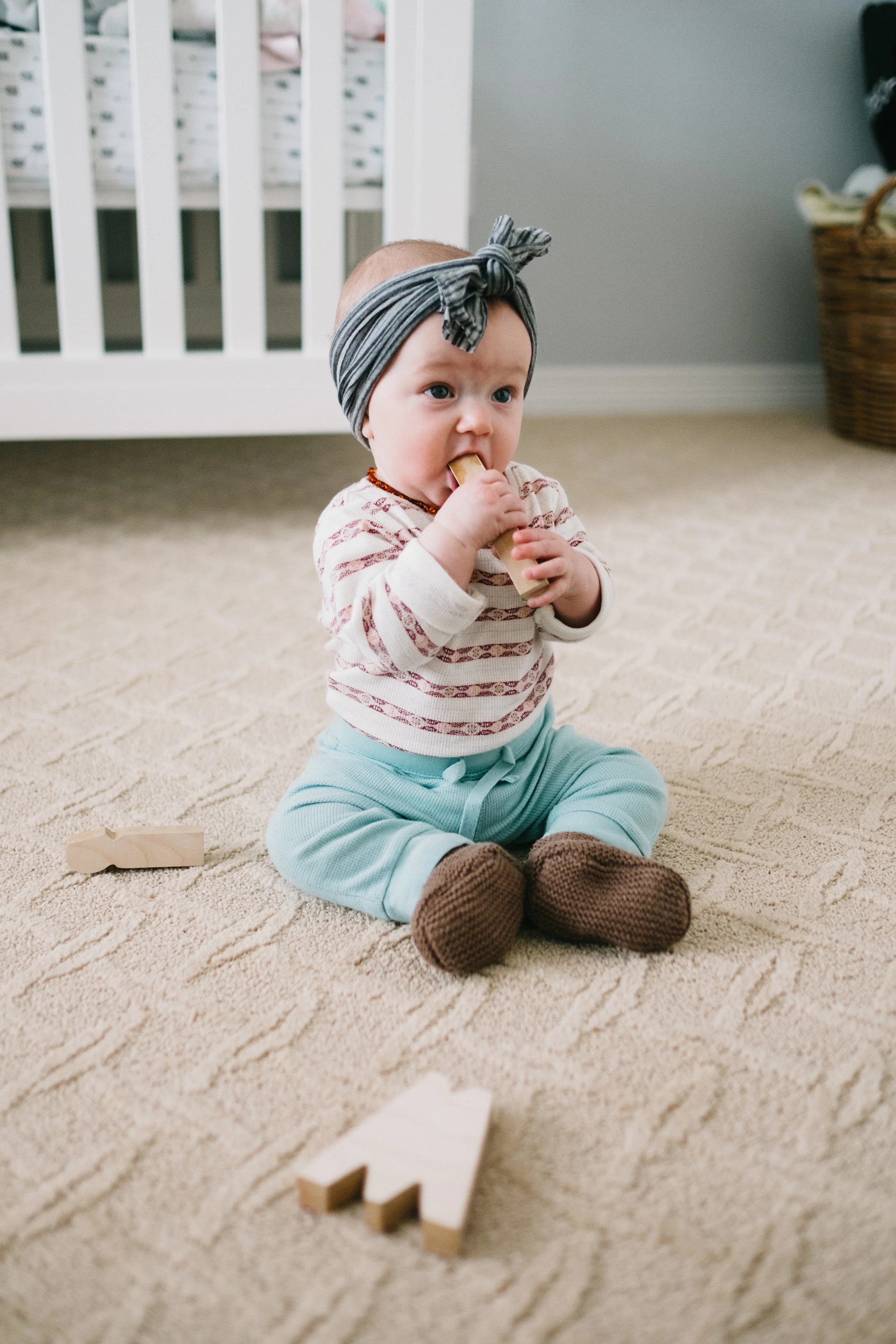 Baby on floor chewing on block