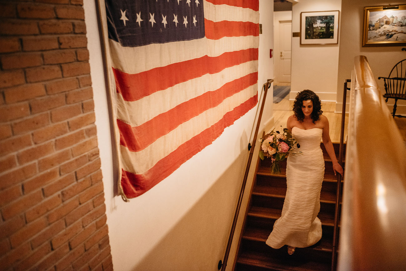 bride getting ready for the ceremony at thte pitcher inn in warren vt next to an american flag