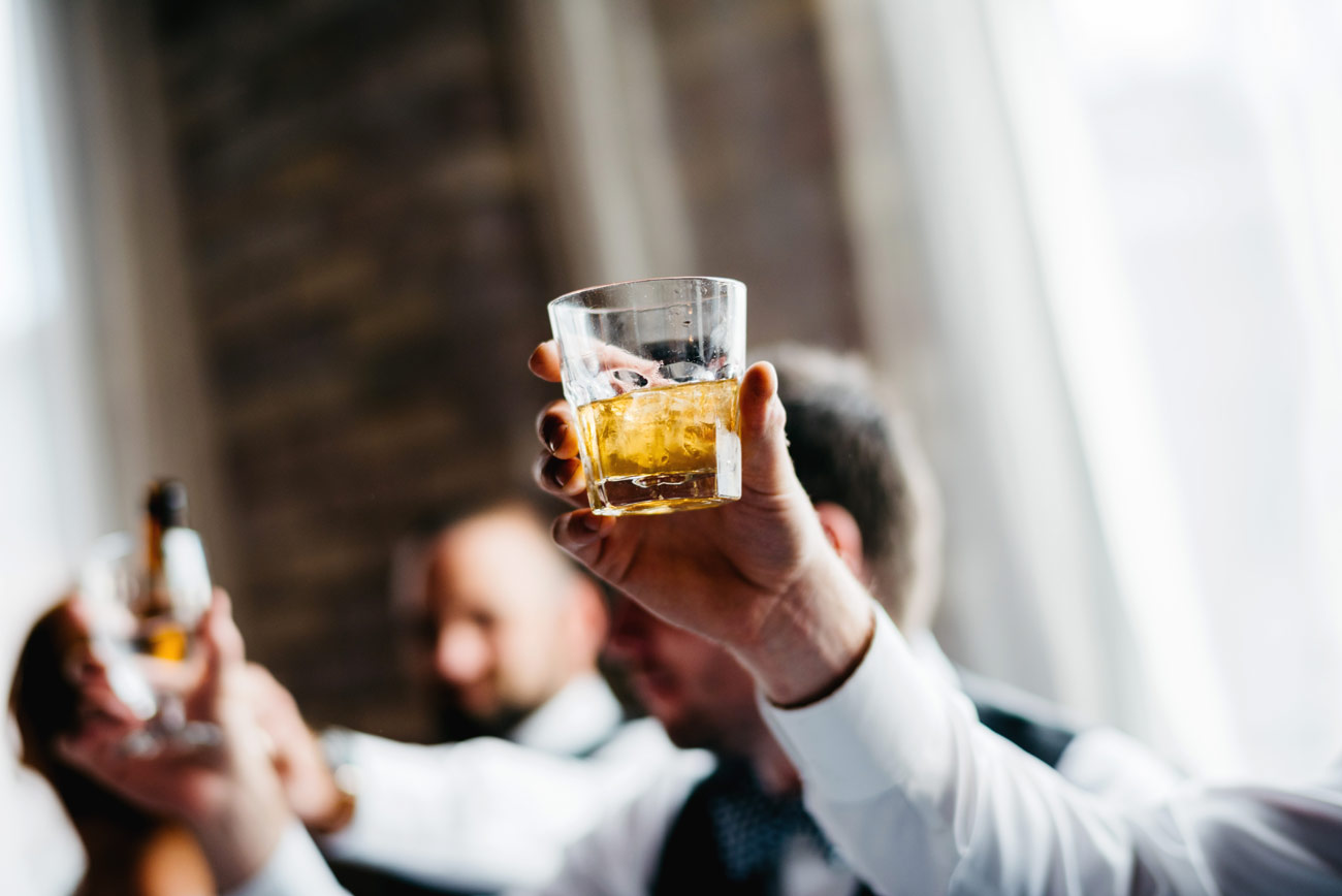 eve at the b.o.b. in michigan cheers and toast by the groomsmen holding a glass of whisky photography