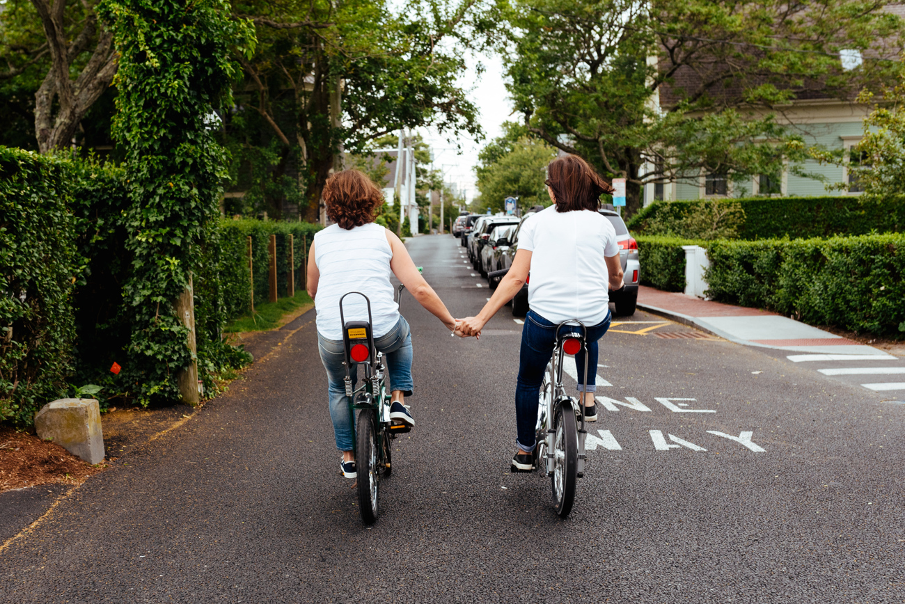 provincetown couple holding hands riding bikes at their elopement