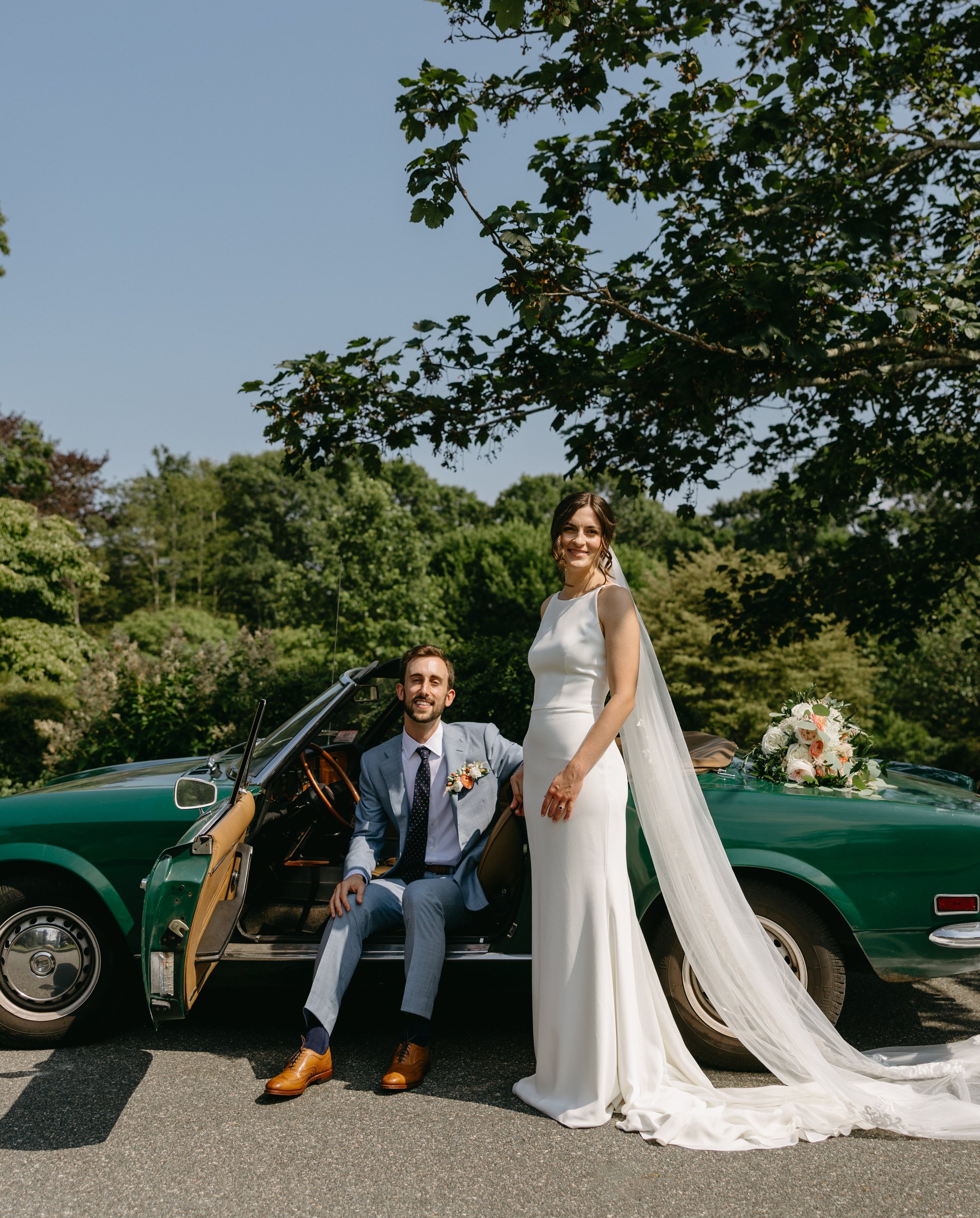 bride and groom posing for an editorial style wedding portrait in front of a green fiat