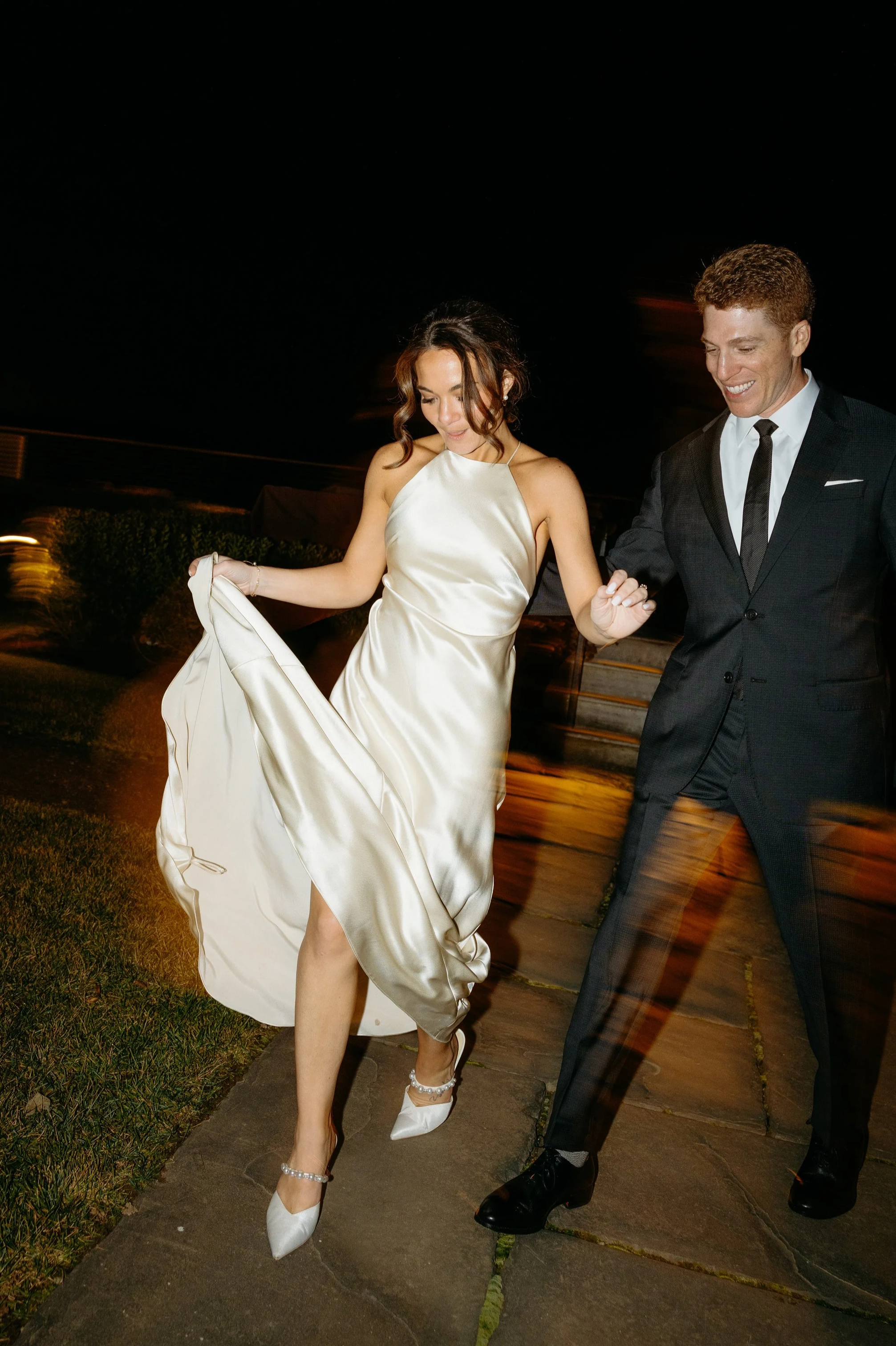 Couple holding hands walking at night at their wedding venue shot in editorial style direct flash ny creative wedding photos