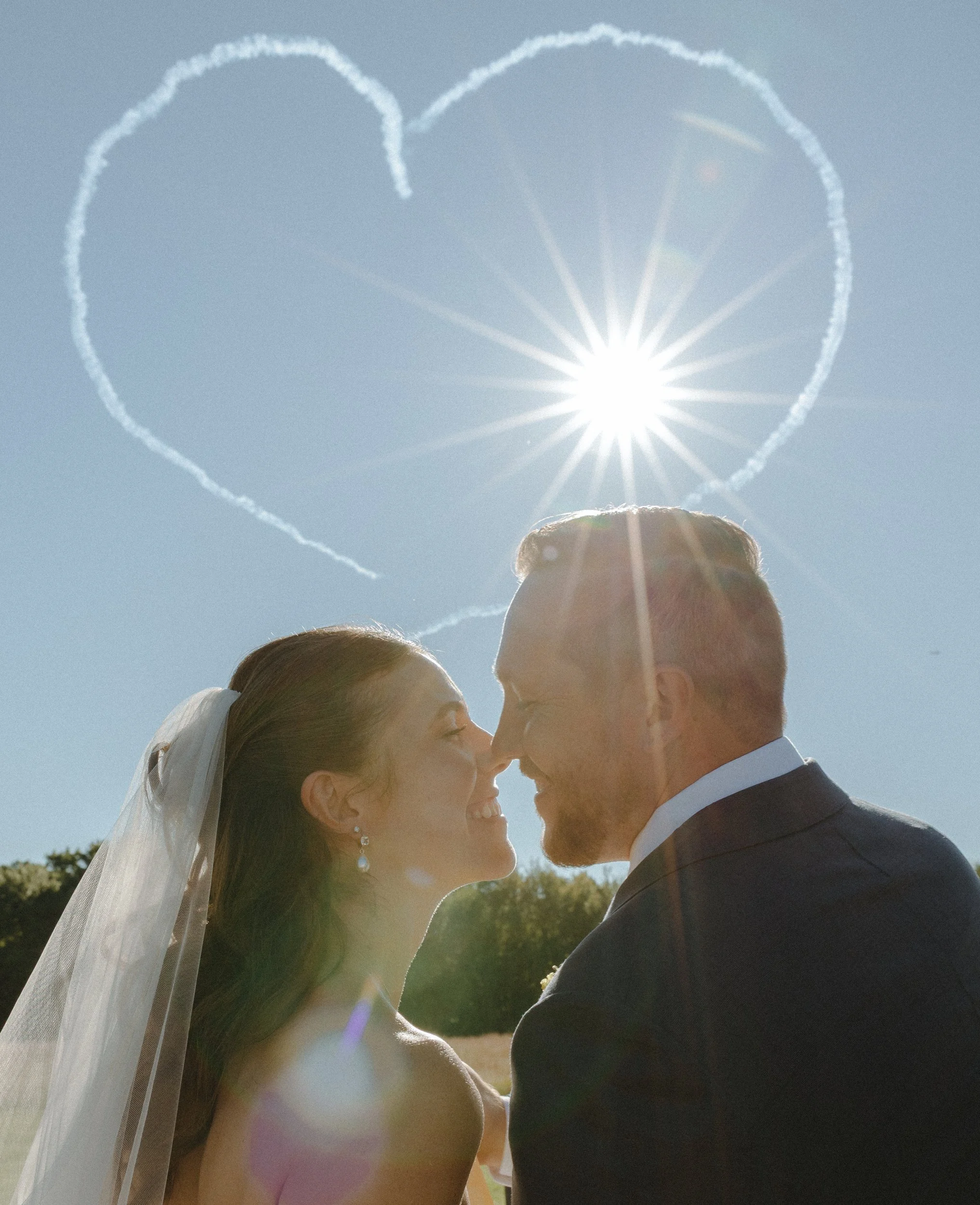 bride and groom going in for a kiss with heart in the sky made by stunt planes