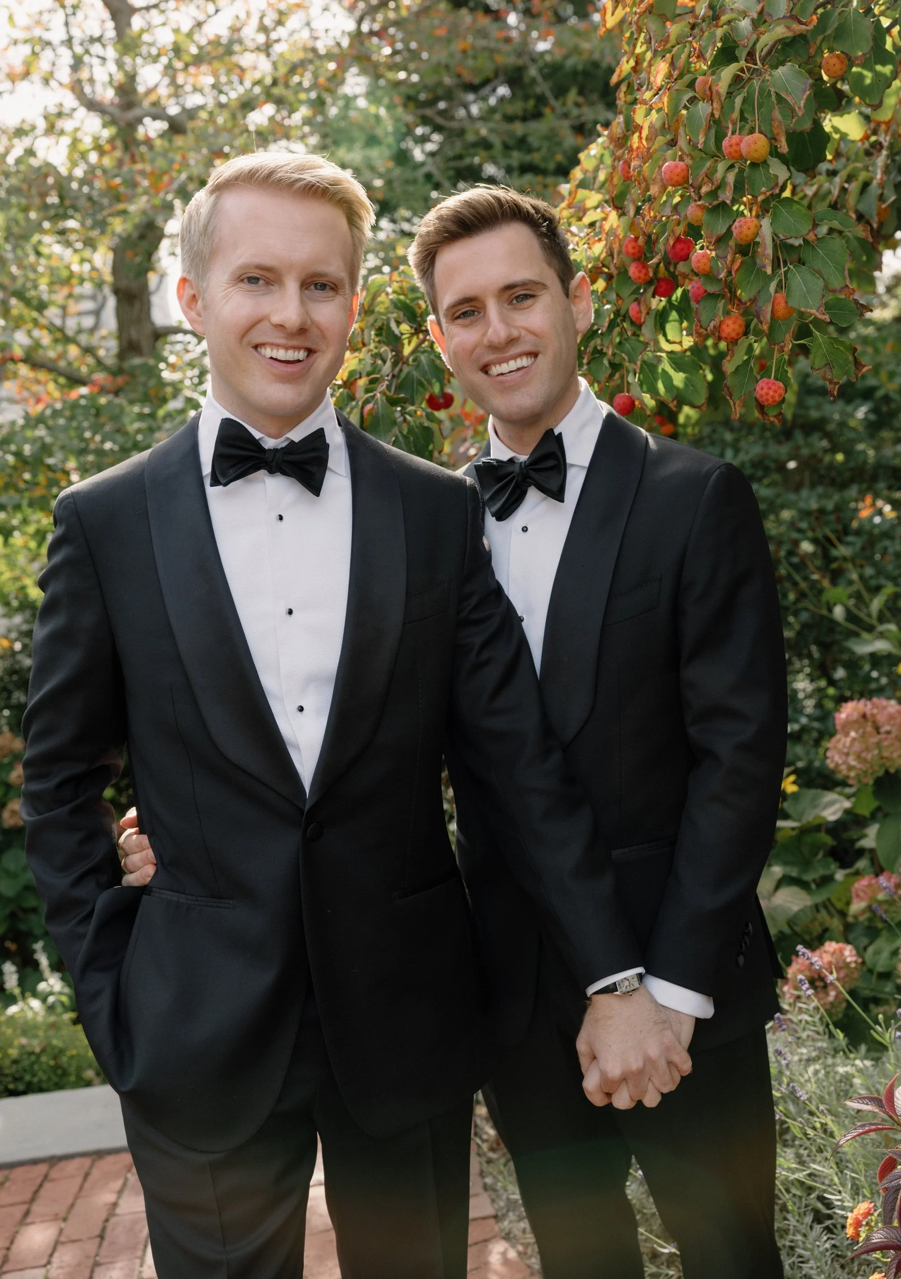 stunning fall portrait of two grooms with black tux's on holding hands in provincetown at their pilgrim monument downtown wedding cape cod