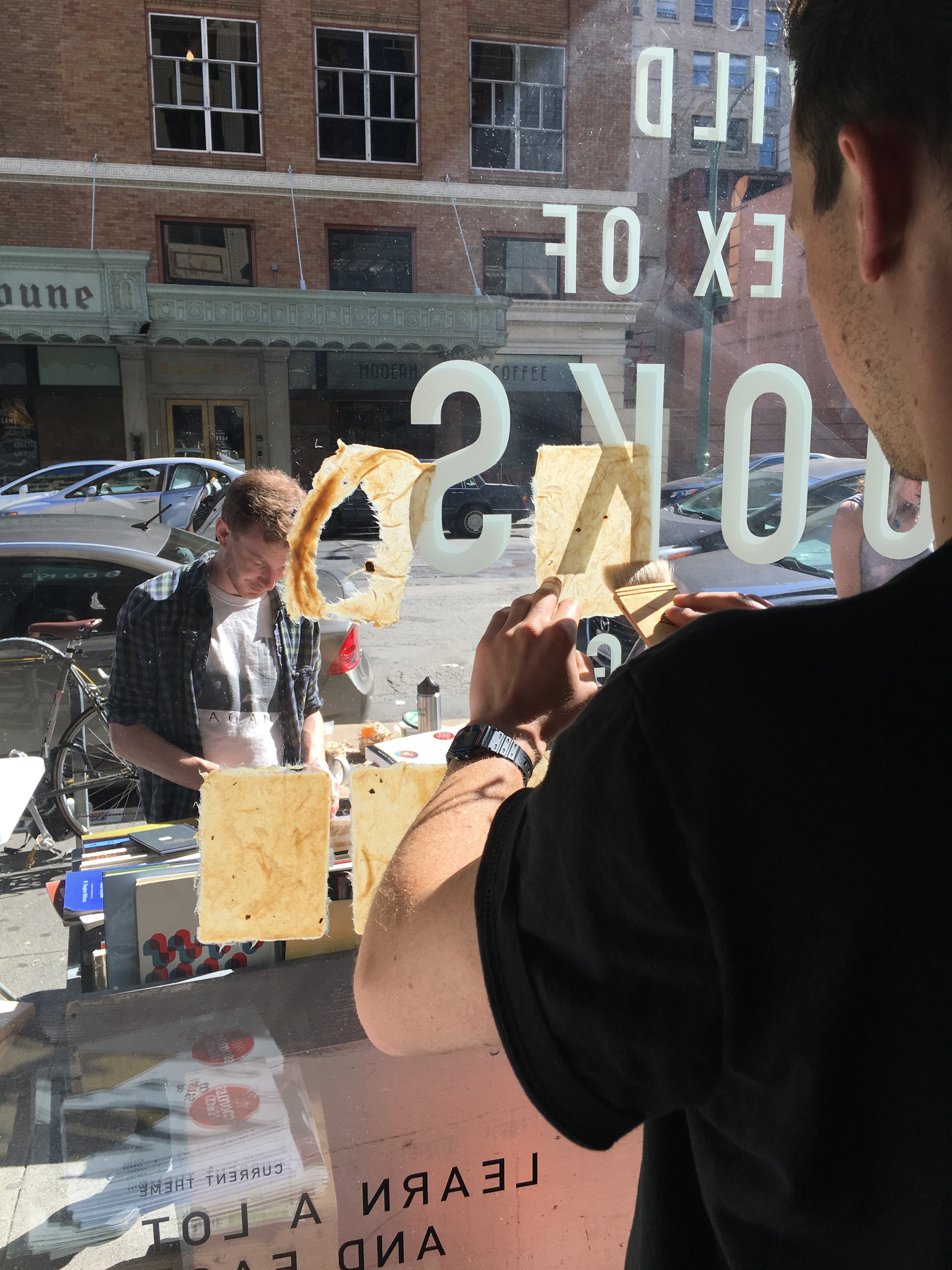 brushing sheets to dry on the bookstore windows as andy works outside.