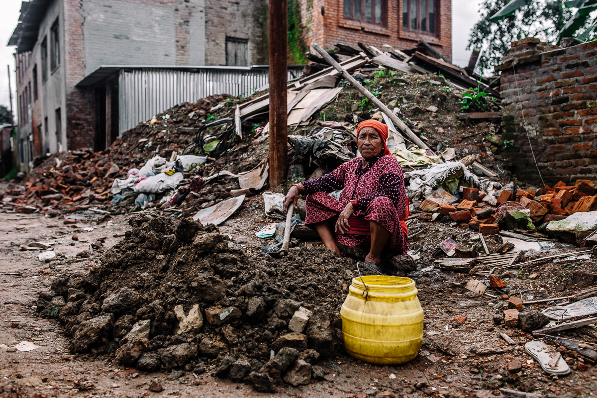 A woman gathers the dirt and mix it with water to create material needed to rebuild her home. Assistance from the government to rebuild the destroyed homes have been slow and inefficient. Sankhu, Nepal | 2015
