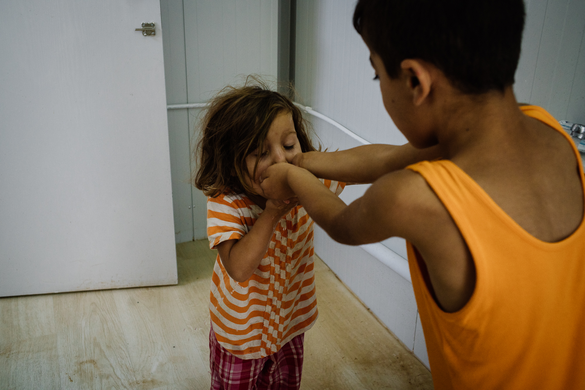  Her frame, small and little, could barely reach for the tap herself. So Muhammad, with a brotherly charismatic charm, steps forward to help Kurdistan by pouring water into his own hands where she will then take a sip from to rinse off the colgate. A