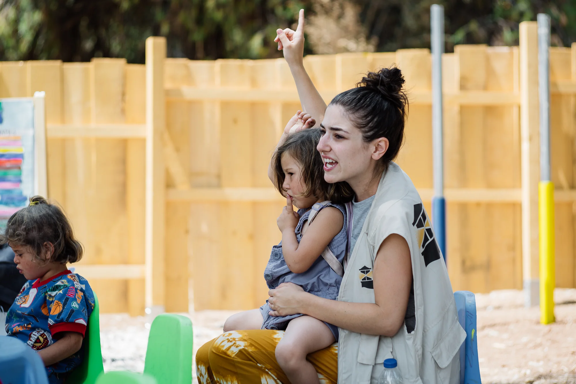 Little Kurdistan seating on her teacher's lap after she started crying again when being asked to walk from the pram to her own seat due to the pain she's feeling in her bruised knee.
