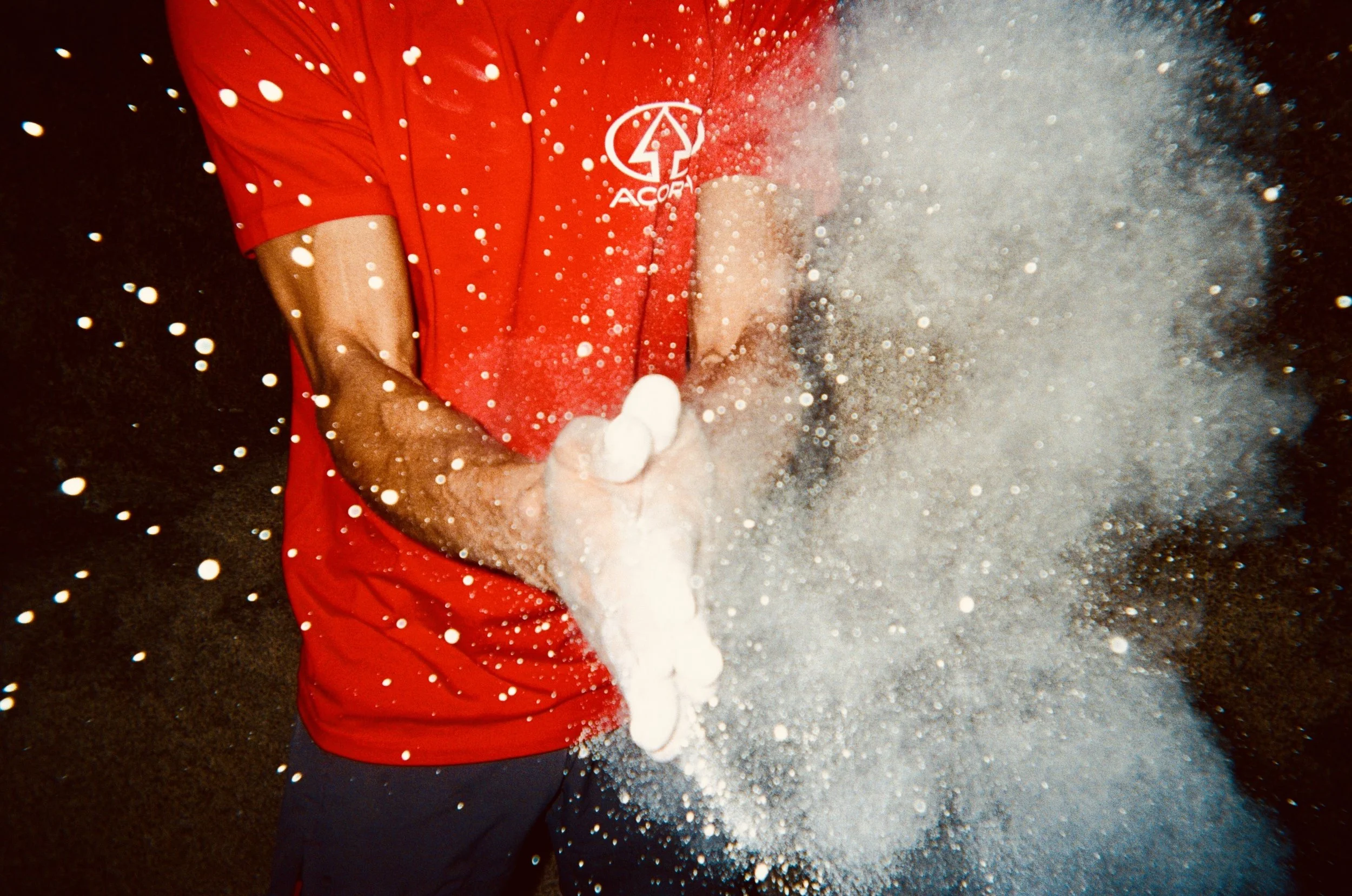 Person wearing a red shirt with a logo, surrounded by white foam or bubbles.