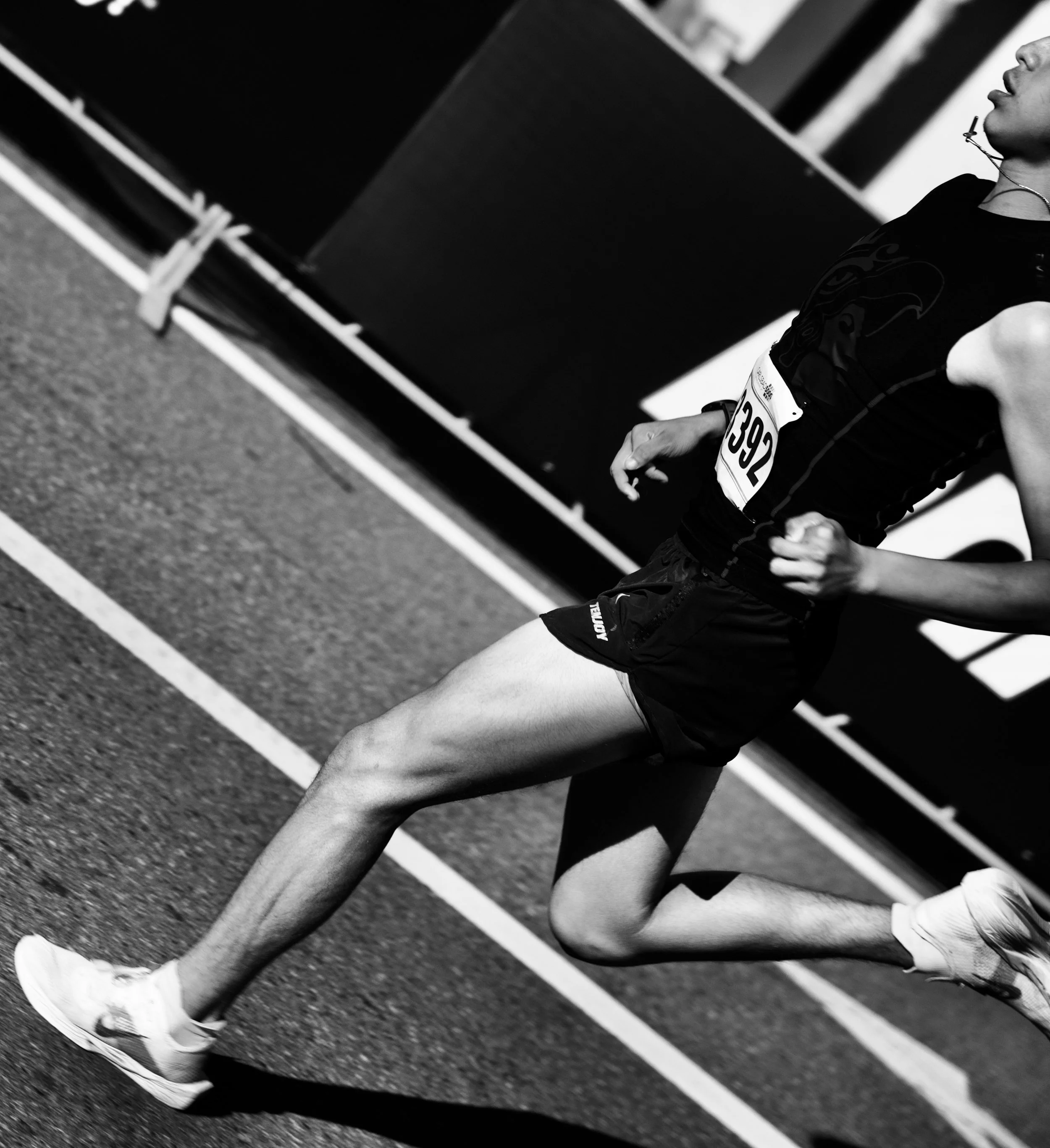 A person in athletic gear, wearing a bib number 392, standing on a running track, likely at a race or sporting event.