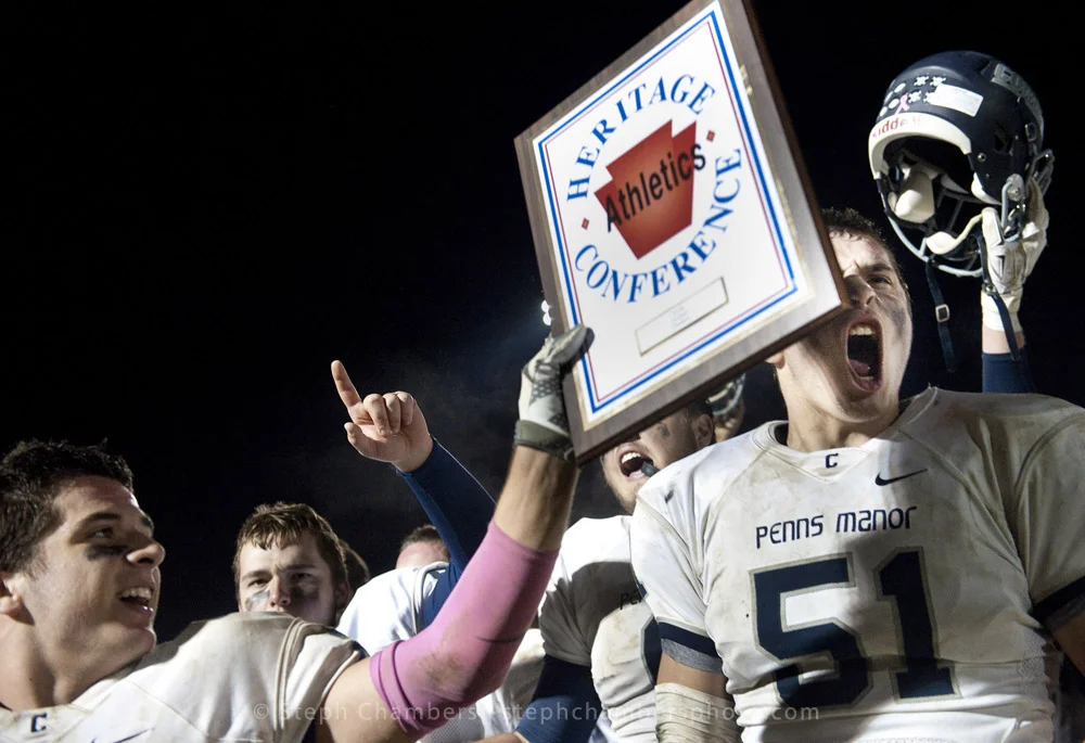 Penns Manor's Bailey Mumau hoists the Heritage Conference plaque as Zach Hnatko reacts after beating Ligonier Valley during a football game on Friday, Oct. 23, 2015 in Ligonier. Penns Manor won 19-12.