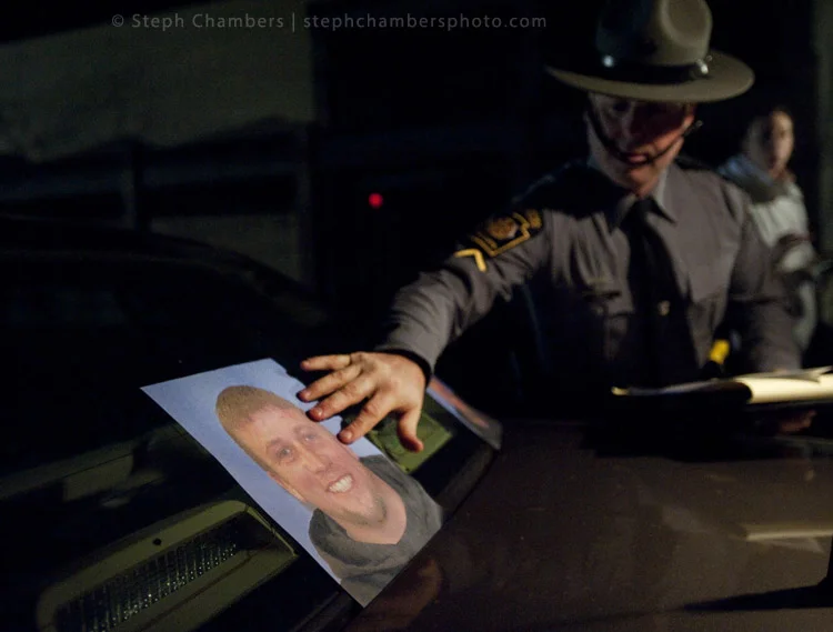 Trooper Stephen Limani lays photo of suspect Ray Shetler Jr., 31 of New Florence, on his police car during a search on Saturday, Nov. 28, 2015 in New Florence.