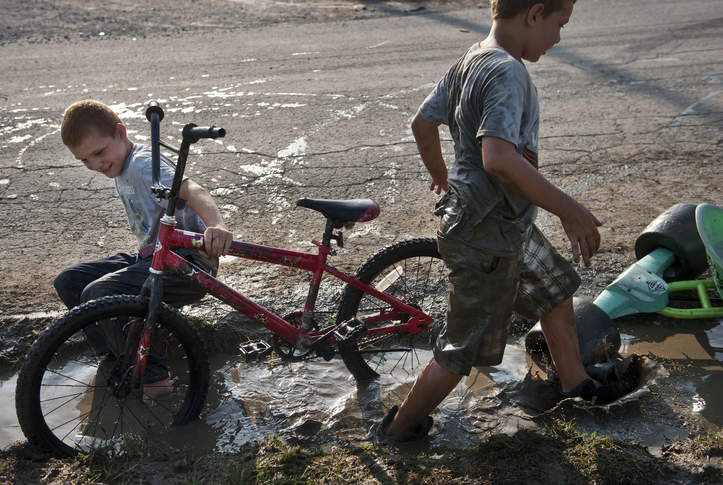 Cammeron Bluey, 9 (left), plays with his brother Logan, 8, in the mud with their bikes while watching a District 31 American Legion baseball playoff game on Thursday, July 7, 2016 in Whitney. The brothers, who dubbed themselves "The Dirtiest Kids in…