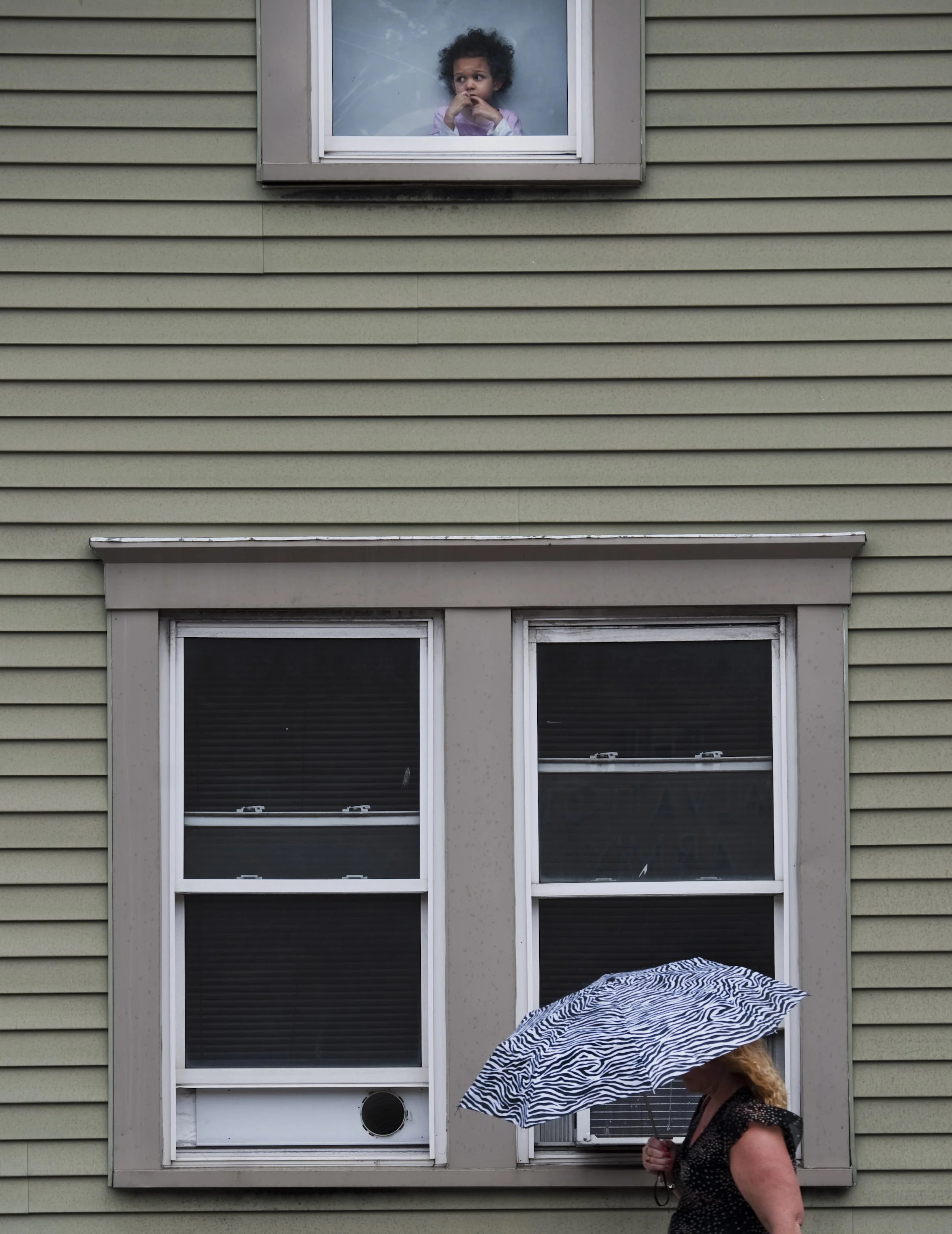 A young girl watches the rain fall as a pedestrian keeps herself dry along Otterman Street in Greensburg on Wednesday, Sept. 14, 2016.