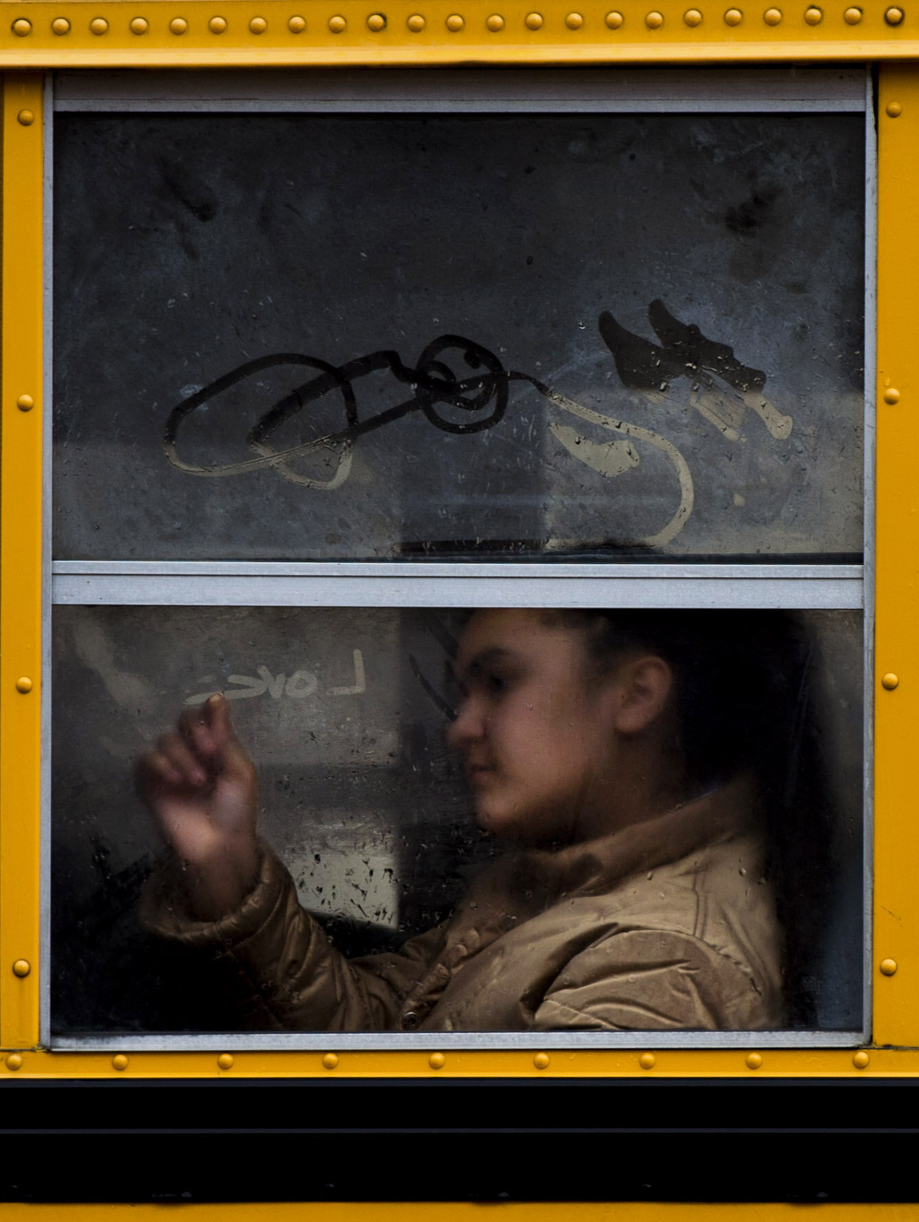  A girl draws with the condensation on a school bus window on Friday, March 31, 2017 while riding along Penn Avenue in East Liberty. 