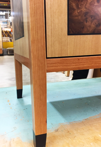A close up to show you the ebony banding that frames the dramatic Carpathian Elm Burl and also adds detail in the foot of the music cabinet.