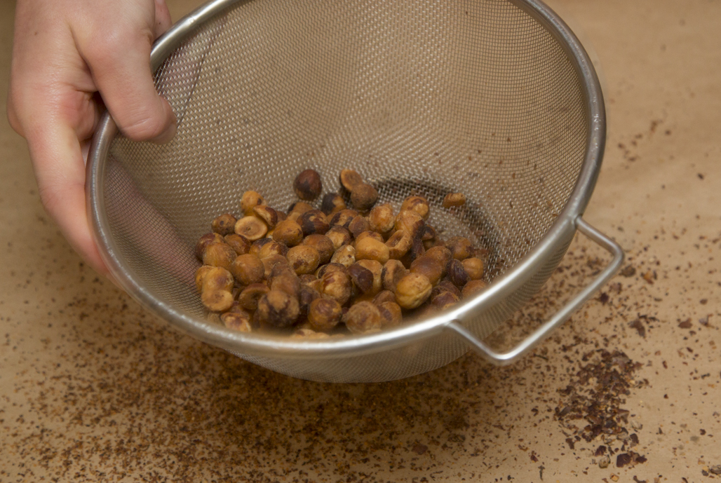 Gently toss the hazelnuts in a sieve to separate smaller bits of skin. 