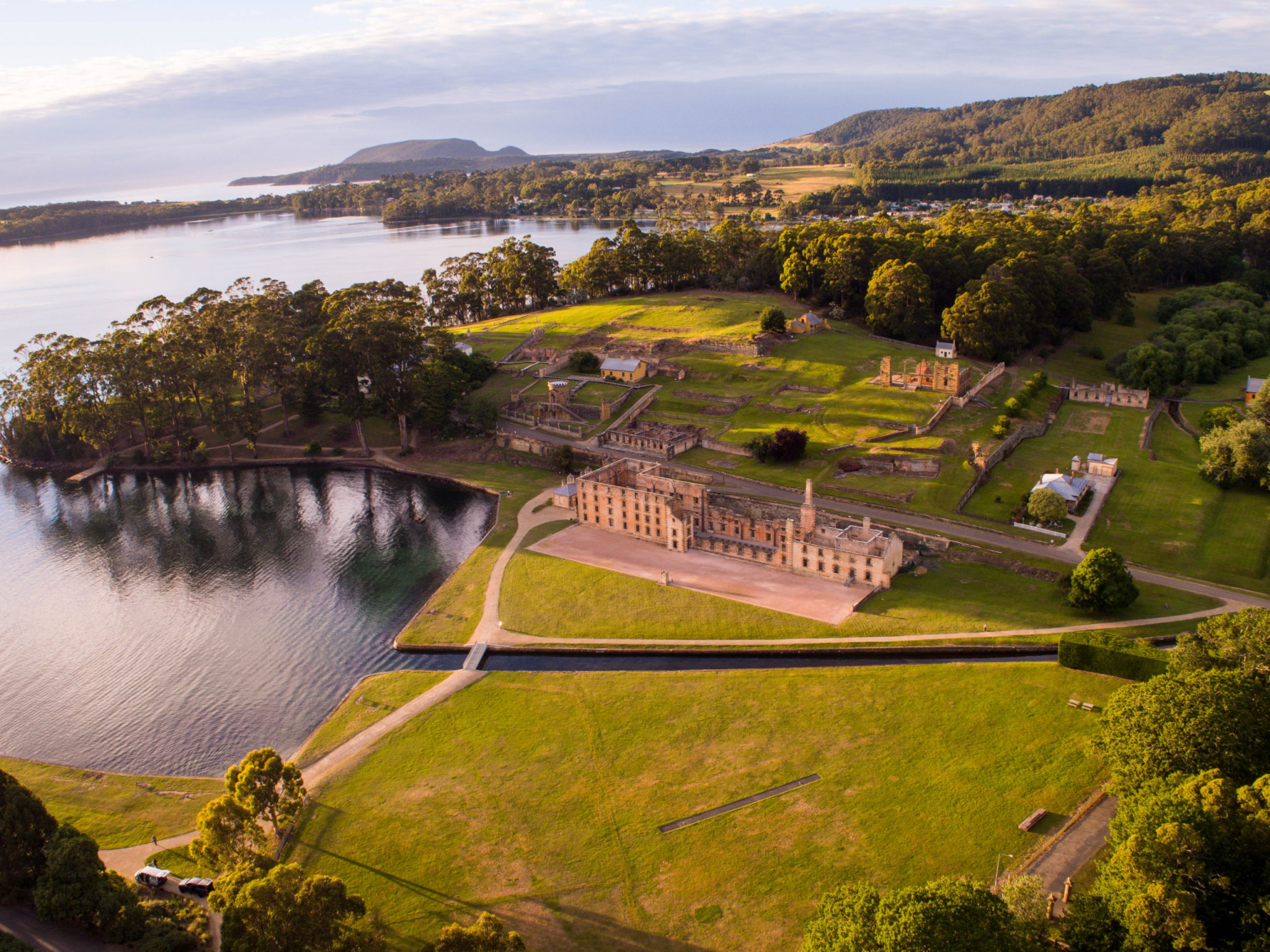 Aerial view of Fort George, a historic seaside fortress with a large building, water surrounding it, and green areas with trees.