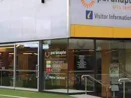 Exterior view of a building with signs for visitor information, paraplane, skydiving, and water sports services