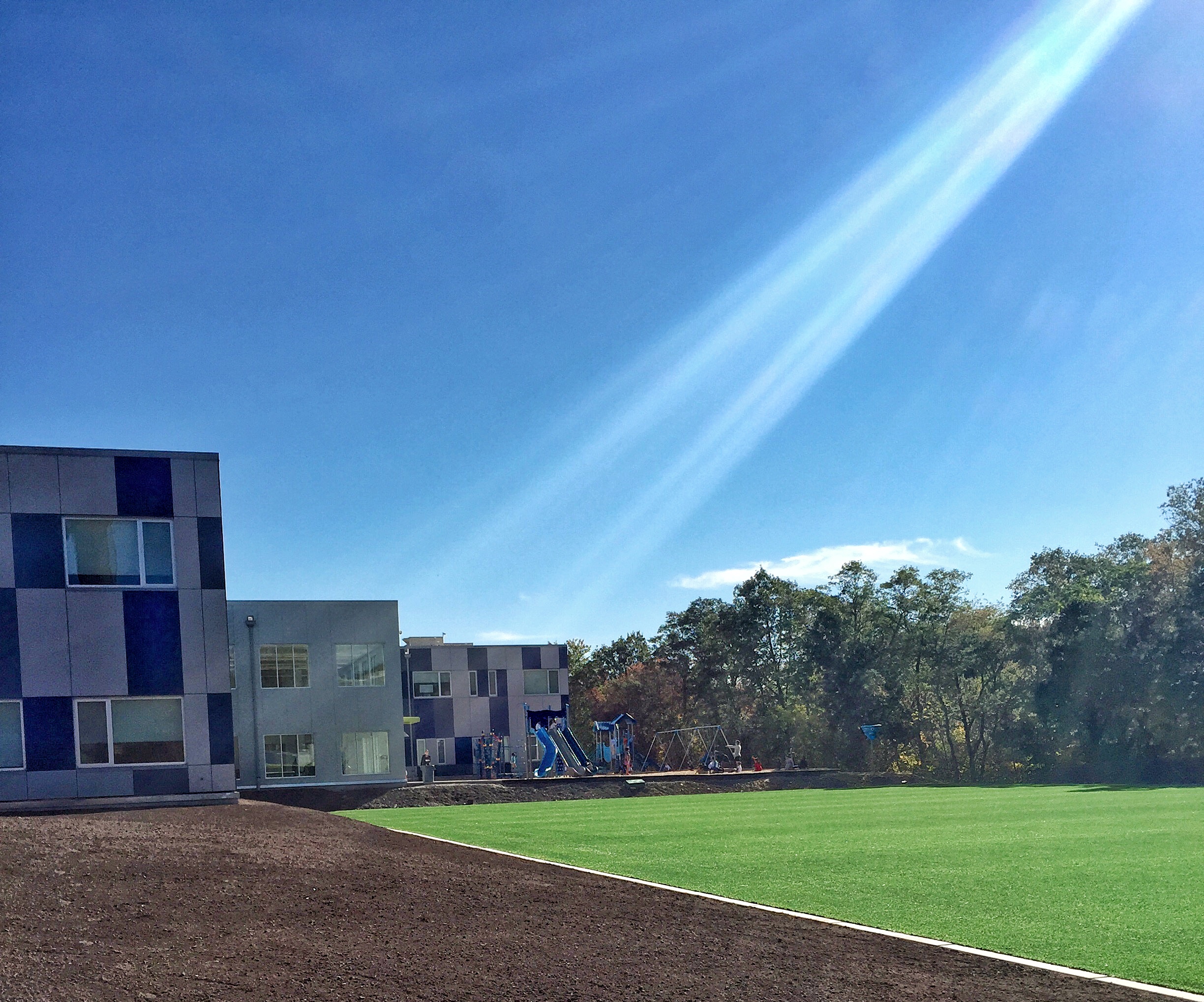 Looking across the turf field towards one of the academic buildings and the playground.
