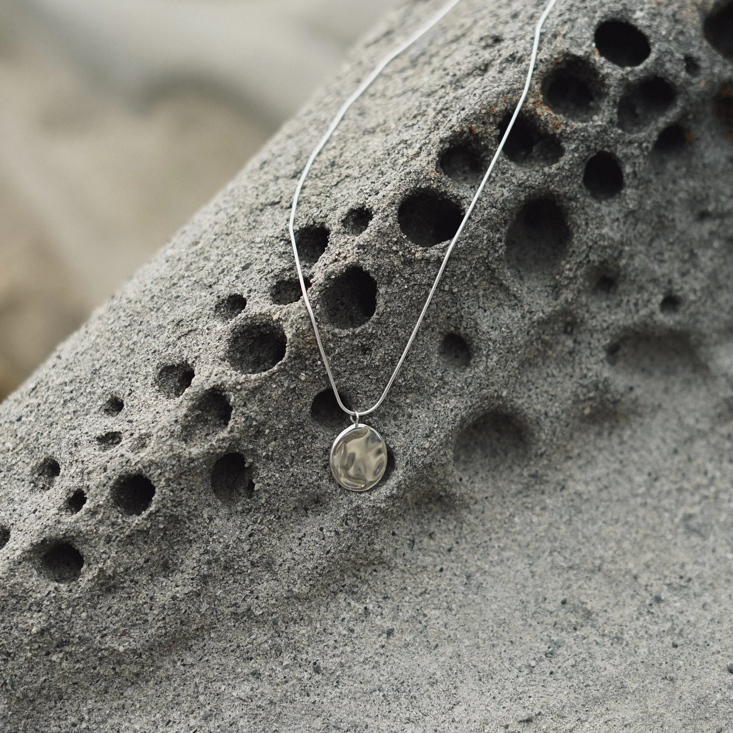 A statement pendant with water ripple texture, suspended on a liquid snake chain. It embodies the spirit of change, as a beautiful life force that carries us toward new destinations and experiences.
