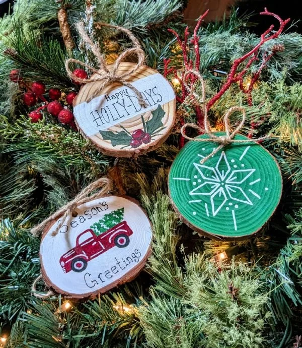Birch rounds painted with holiday themed images on evergreens