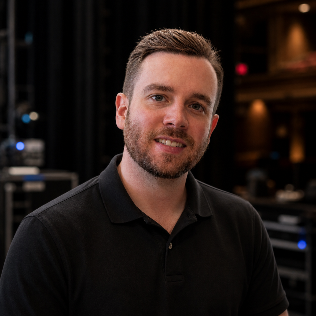 Image of Caucasian man with short brown hair and facial hair wearing a black polo