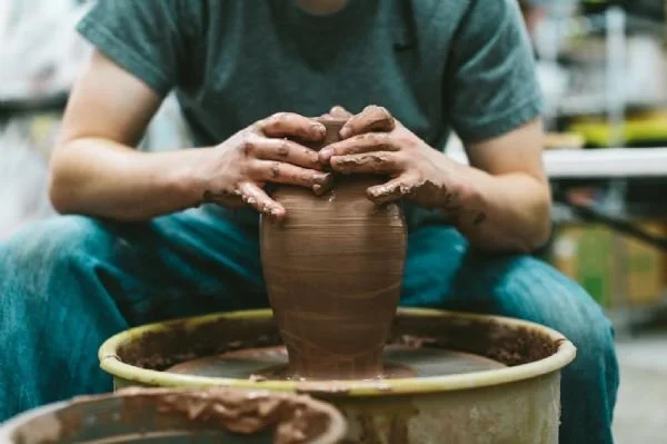 Image of artist throwing clay on a wheel.
