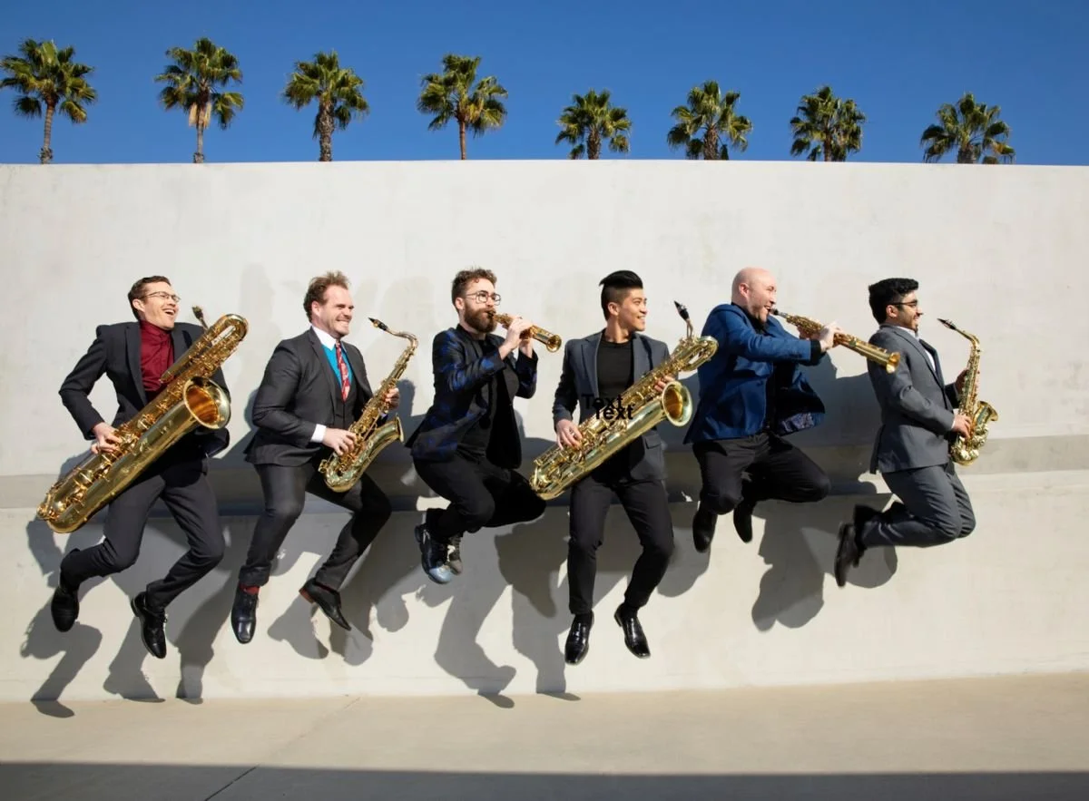 Six musicians holding their jazz instruments jumping on a sidewalk.
