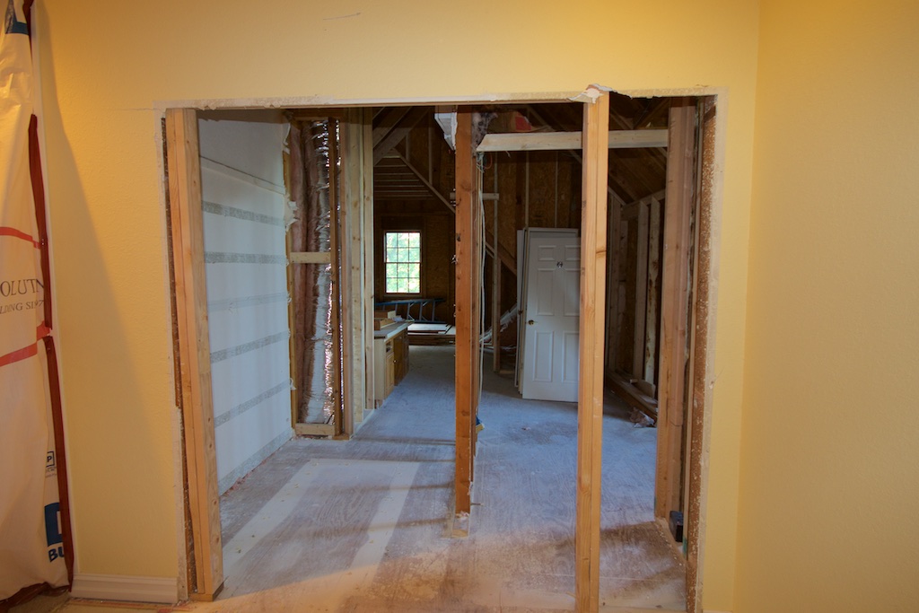 In this pic, I was standing at the end of the upstairs hall. On the very left, you can see some of the plastic that they put up over stairway entry. We're looking at the new entrance into the studio wing. The entry will be french doors. The framing that you see just inside the attic, almost in the middle, is what remains of the linen closet. Our alarm system is at the top of that wall. Until Advanced Alarms makes it out here on Thursday and moves the panel, that framing has to stay. That grayish, striped wall on the left of that framing, is the stairwell, minus the insulation. 