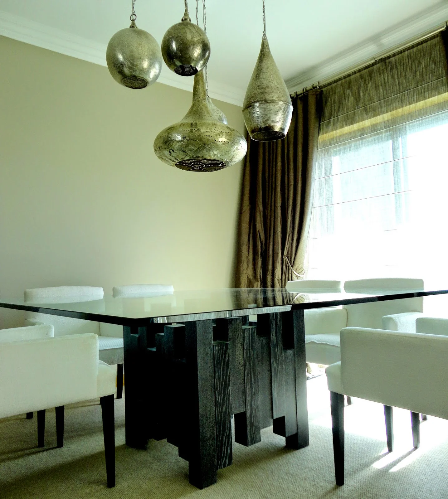 Uma imagem aparentemente simples, mas que precisa de mais tempo para ser apreciada. Primeiro olhemos para a mesa: simplesmente grandiosa, com um pé central com tanto movimento como aquele que gostamos de sentir quando rodeados por amigos e familia num jantar. E agora apreciemos o candeeiro: contemporâneo de inspiração marroquina, abat-jours perfurados fazem umas sombras lindas espalhadas pelas paredes e tectos. 