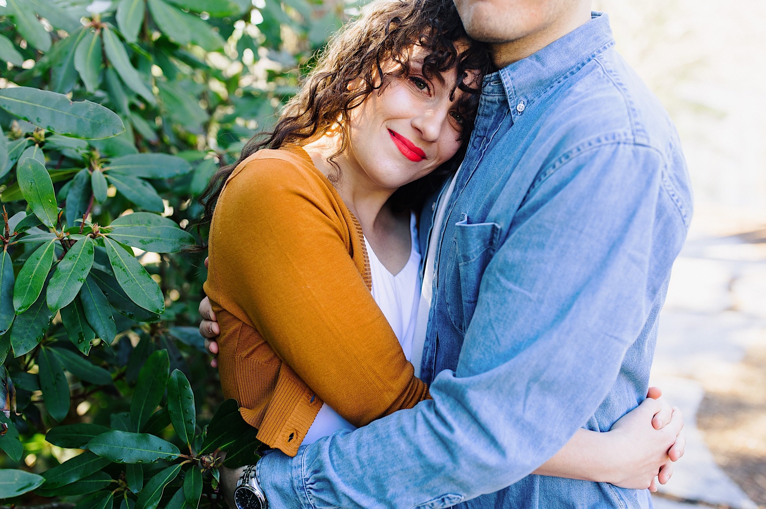 011-engaged-couple-hugging-near-bush.jpg