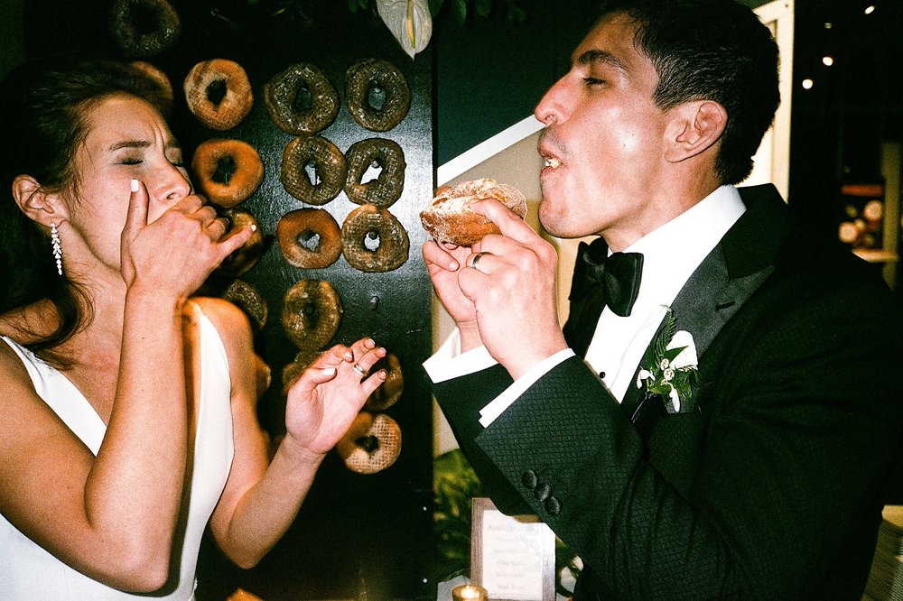 Film-ZacWolfPhoto-4_Bride and groom eating a doughnut.jpg