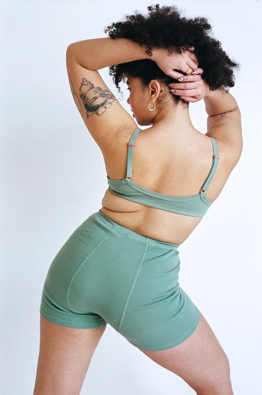 Rear photo of a woman stretching in Pansy Stretch Shorts in Mermaid.